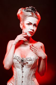 Red Queen with a crown and a corset, with make-up in studio shot