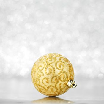 Single golden christmas ball on shiny silver background