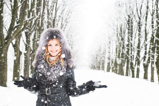 Woman is walking in park alley in winter