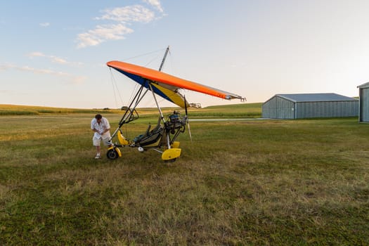 Pilot checks microlight aircraft early morning before flying.