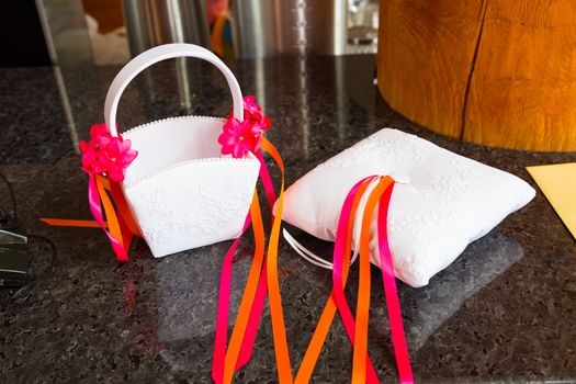 A flower girl basket and pillow of a ring bearer sit on it's own while waiting for the wedding ceremony to start.