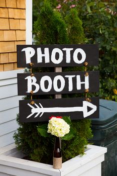 A handmade sign reads photo booth with an arrow pointing the wedding guests to the photobooth location.