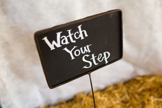 A wedding chalkboard sign says watch your step at a reception.