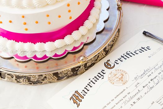 A wedding cake sits next to the bride and groom marriage certificate at this ceremony and reception.