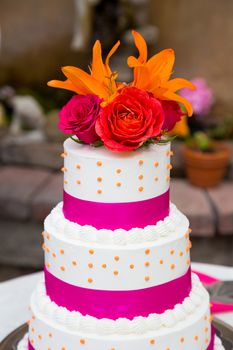 A beautiful wedding cake is set up at the reception for a bride and groom.