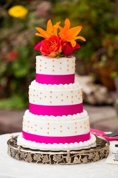 A beautiful wedding cake is set up at the reception for a bride and groom.