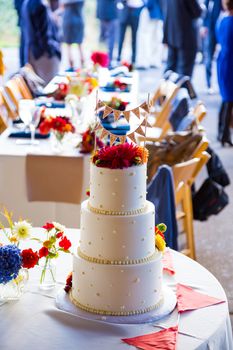 A beautiful wedding cake is set up at the reception for a bride and groom.