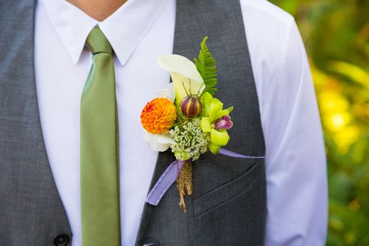 A groom wearing a boutineer on his wedding day made from natural flowers and plants.