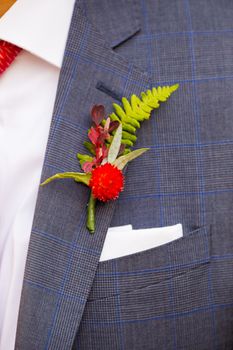 A groom wearing a boutineer on his wedding day made from natural flowers and plants.