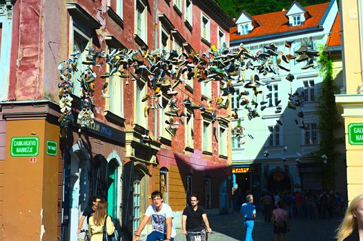 Ljubljana, Slovenia - September 2, 2013: People are passing by famous place where shoes hanging on wire in the Old Town of Ljubljana.