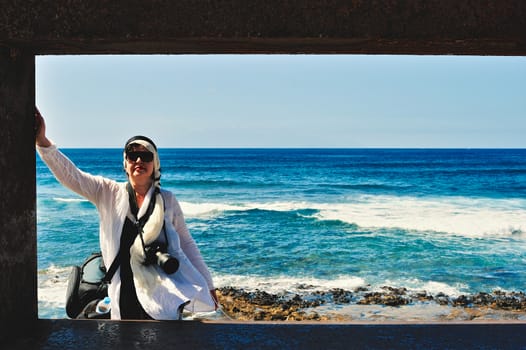 Woman with camera on the volcanic beach. Tenerife, Spain