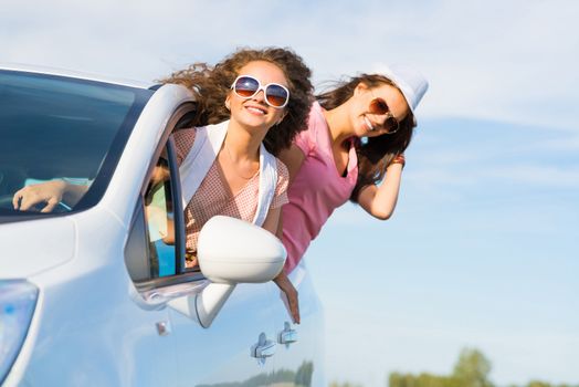 young attractive woman in sunglasses got out of the car window and laugh