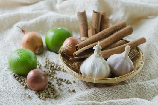 food ingredients on sackcloth ( garlic , onion , lime , peppercorns and cinnamon )