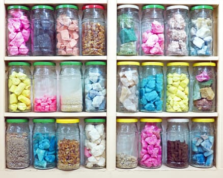 assortment of glass jars on shelves in herbalist shop in marrakesh, morocco, containing herbs and spices for medicinal and culinary purposes