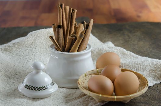 Bowl with cinnamon sticks and eggs on basket