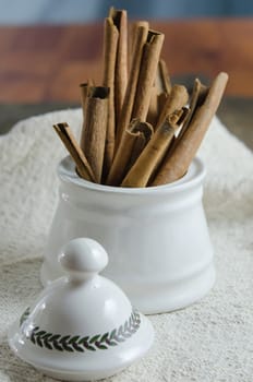 close up white  bowl with cinnamon sticks on  sackcloth