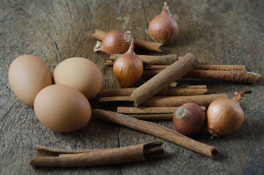 eggs, cinnamon sticks and onion  on wooden background