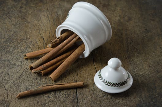 White  bowl with cinnamon sticks on  wooden background