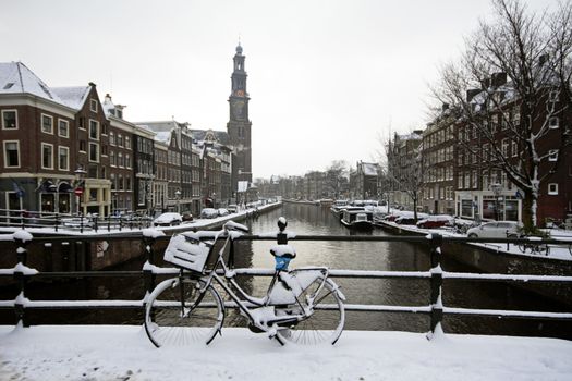 Amsterdam covered with snow with the Westerkerk in winter in the Netherlands