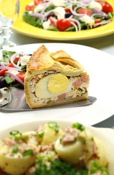 Delicious slice of baked ham and egg pie with salad ready to serve.