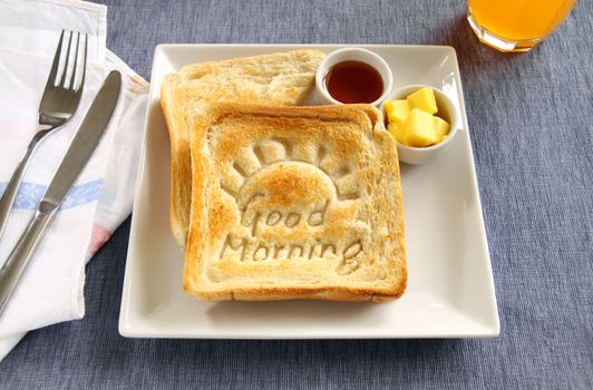 Slice of toast with Good Morning carved into it with butter and honey.