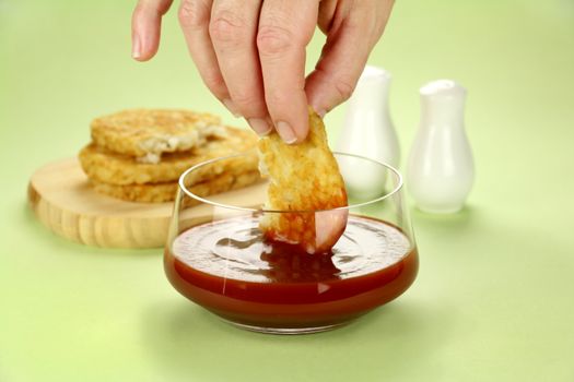 Dipping hash browns into a bowl of ketchup for breakfast.