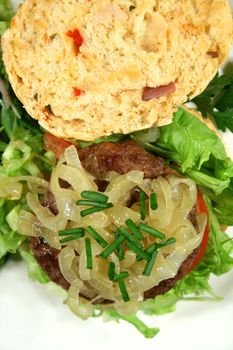 Gourmet beef burger on a fresh homemade herb roll with caramelized onion.