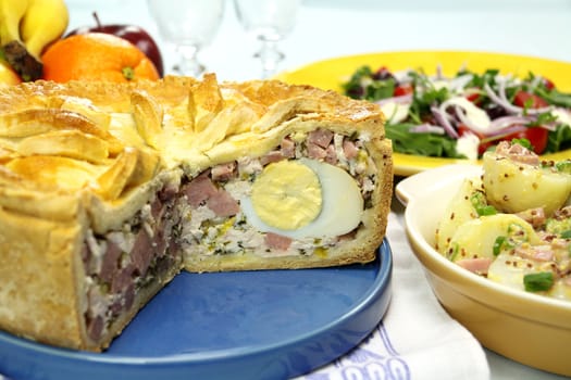 Sliced ham and egg pie with potato salad ready to serve.
