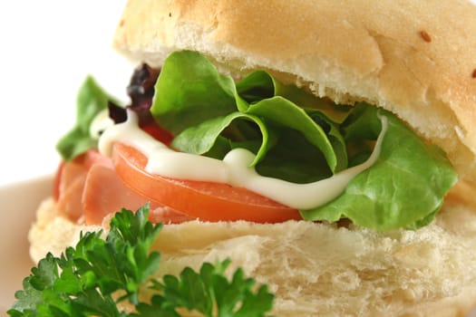Freshly prepared ham and salad roll with mayo.