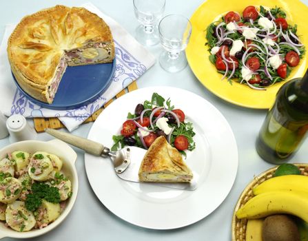 Delicious baked ham and egg pie with potato and salad ready to serve.