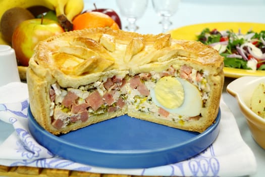 Sliced ham and egg pie with salad and fruit ready to serve.