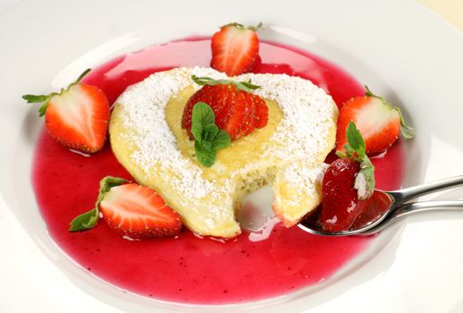 Heart shaped pancake with a spoonful taken out of it.