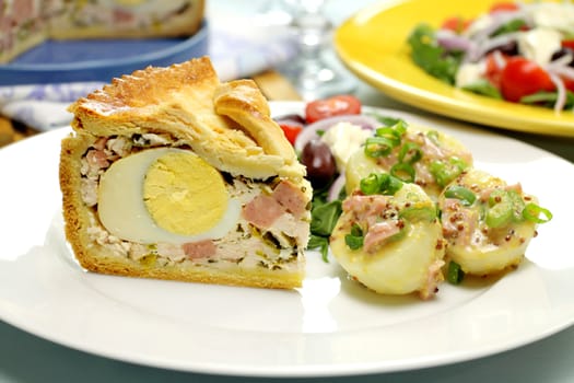 Sliced ham and egg pie with potato salad ready to serve.