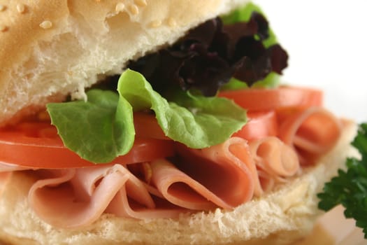 Freshly prepared ham and salad roll with sesame seeds.