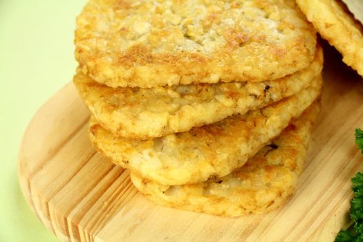 Stack of fried hash browns on a board ready to serve.