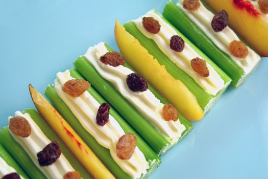 Healthy afternoon snack of celery sticks with cream cheese and sultanas.