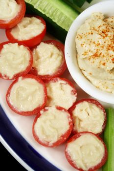 Stuffed cherry tomatoes with hummus and cucumber.