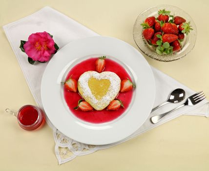Delightful heart shaped pancake with fresh strawberries and a strawberry sauce.