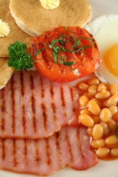 Breakfast of grilled bacon, tomato, egg, baked beans and pancakes.