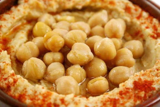 Earthenware bowl with delicious hommus and chickpeas ready for dipping.