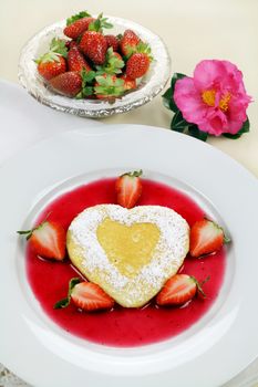 Delightful heart shaped pancake with fresh strawberries and a strawberry sauce.