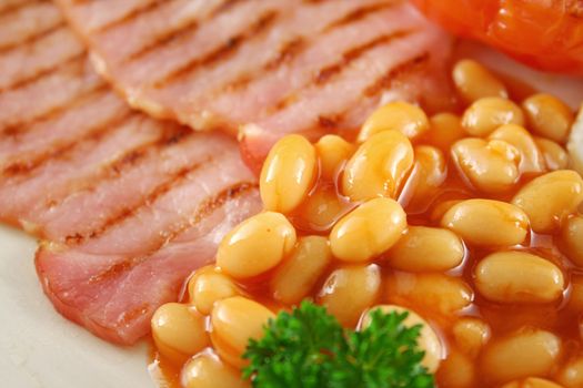 Breakfast of grilled bacon, tomato, egg and baked beans.