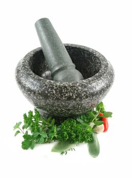 Fresh herbs with garlic and chilli ready to crush in a mortar and pestle.