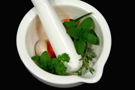 Fresh herbs with garlic and chilli ready to crush in a mortar and pestle.