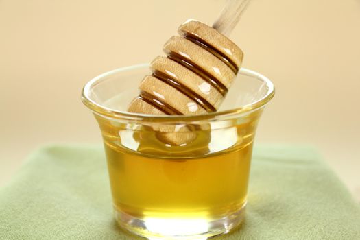 Honey twirler dipped into a glass of honey and about to be lifted.