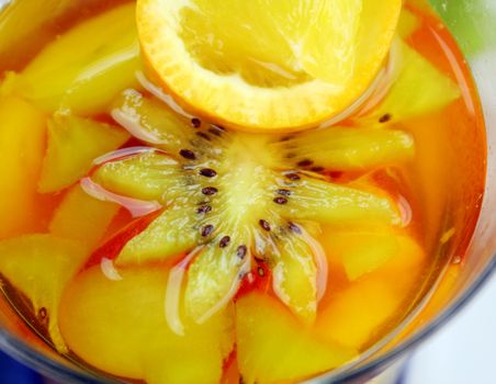 Fresh sliced tropical fruit set in pineapple jelly in a glass.