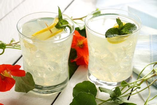 Delicious iced lemon drinks with sliced fresh lemon and mint.