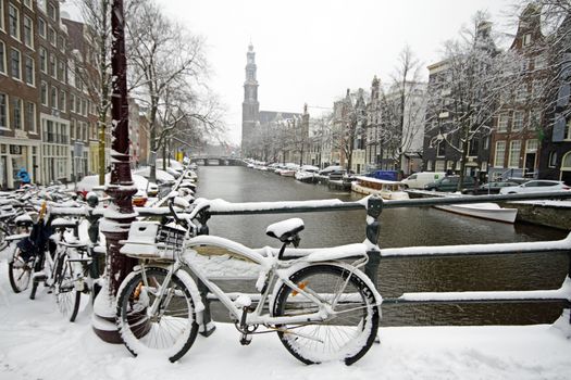 Amsterdam covered with snow with the Westerkerk in winter in the Netherlands