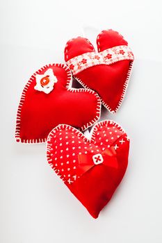 Sewed handmade red hearts on a white background