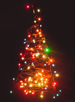 Blurred colorful lights as a silhouette of Christmas tree on black